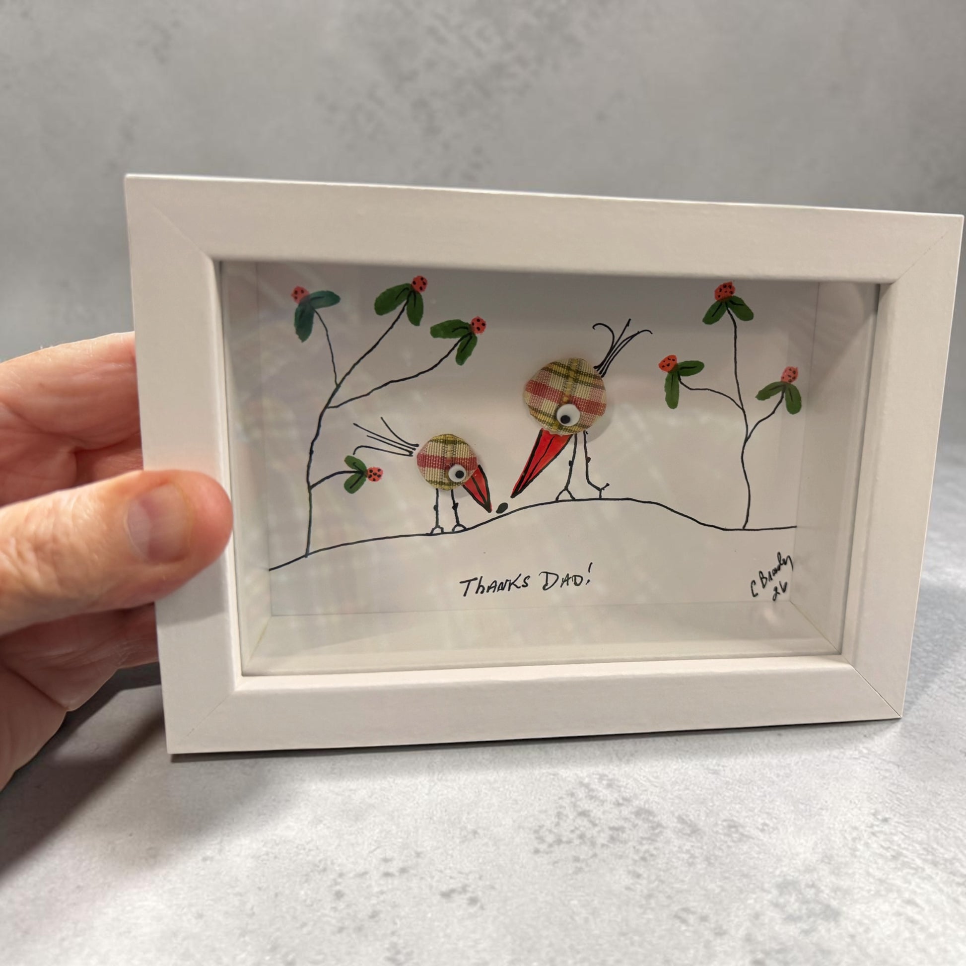 Framed artwork with cartoon-style birds and text 'Thanks Dad!' on a gray background